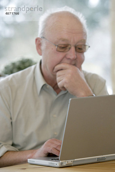 Mann  Senior  sitzt vor einem Laptop