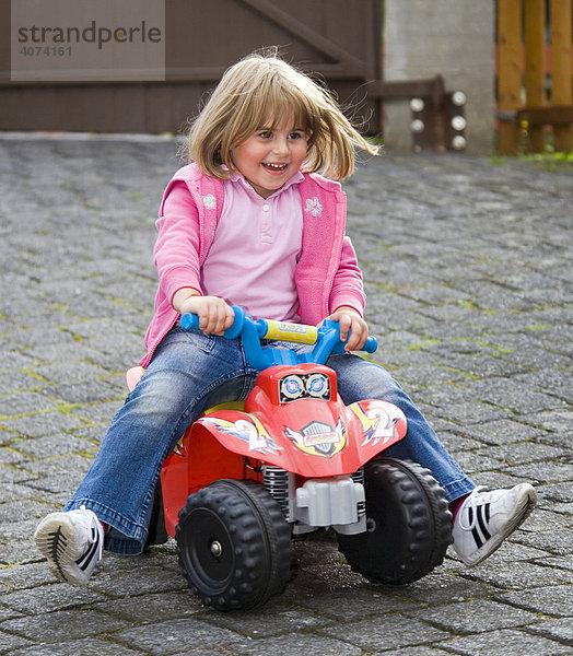 Ein Mädchen  drei Jahre  fährt auf einem Spiel-Fahrzeug