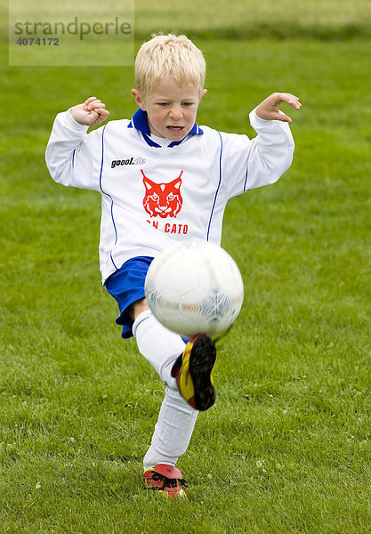A boy  aged four  kicking a soccer ball