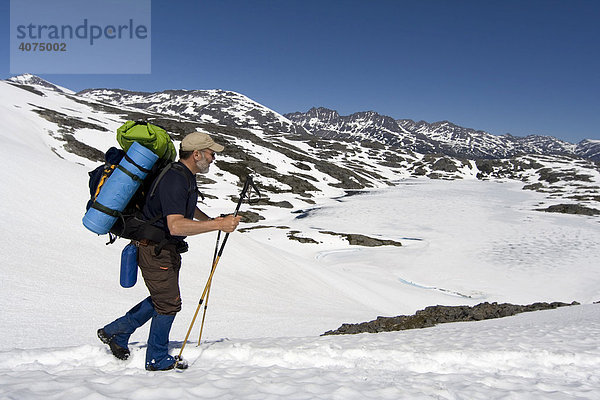 Bergsteiger mit Rucksack überquert ein schneebedecktes Feld  Chilkoot Trail  Chilkoot Pass  British Columbia  B.C.  Kanada  Nordamerika