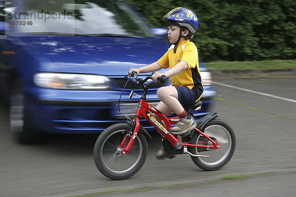 Fünfjähriger Junge fährt Fahrrad und trägt einen Fahrradhelm