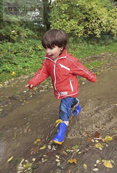 Kind läuft mit Gummistiefeln durch Pfützen  Niederwerth  Rheinland-Pfalz  Deutschland  Europa