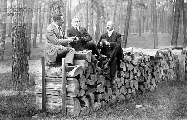 Männer sitzen auf gestapeltem Holz  historische Aufnahme  ca. 1920