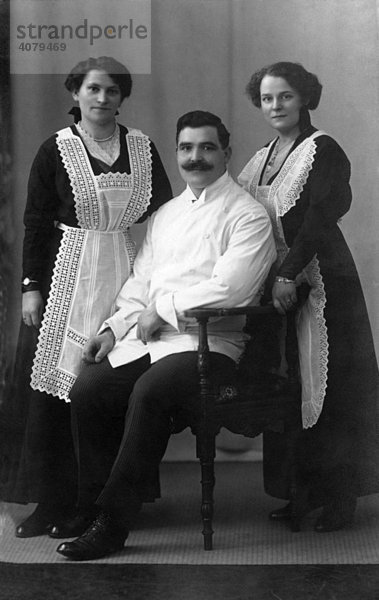 Mann sitzt  Frauen stehen  historische Aufnahme  ca. 1920
