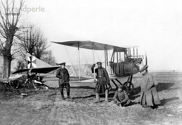Historische Aufnahme  Erster Weltkrieg  Luftwaffe  Deutsches Flugzeug in der polnischen Tiefebene an einem Baumstumpf verankert. Die beiden Flieger führen Bomben.