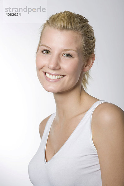 Portrait einer lachenden jungen Frau im weißen Shirt