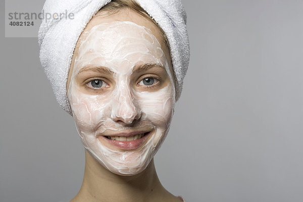 Junge Frau mit Gesichtsmaske und weißem Handtuch