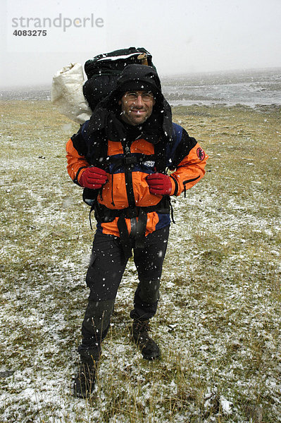 Trekking Bergsteiger mit Rucksack im Schneefall in der Steppe Kharkhiraa Mongolischer Altai bei Ulaangom Uvs Aimag Mongolei