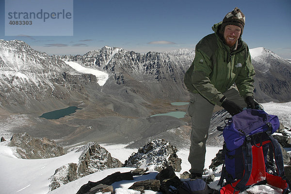 Bergsteiger mit Rucksack auf einem Gipfel mit Ausblick in die Bergwelt des Turgen Uul Kharkhiraa Mongolischer Altai bei Ulaangom Uvs Aimag Mongolei
