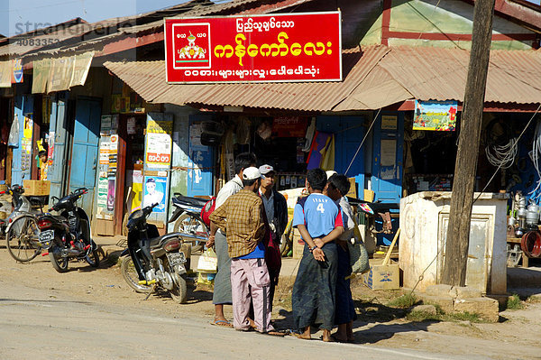 Männergruppe vor Geschäft mit Schild in burmesischer Schrift Pindaya Shan State Burma