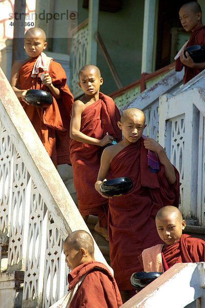 Novizen in roten Roben laufen hintereinander eine Treppe hinunter Maing Thauk Wald Kloster Shan State Burma