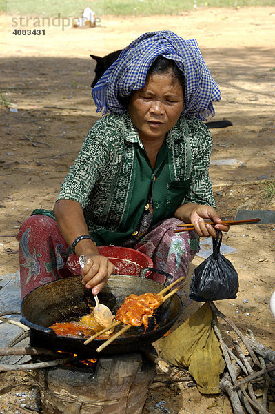 Frau mit Tuch auf dem Kopf grillt Fleischspieß Phnom Santuk bei Kompong Thom Kambodscha
