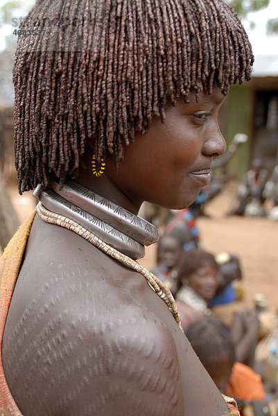 Frau vom Volk der Hamar mit typischer Lehm Haarfrisur mit Schmucknarben auf der Schulter auf dem Markt von Dimeka Äthiopien