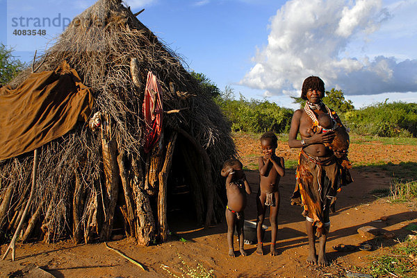 Mutter mit Kindern und Baby auf dem Arm vom Volk der Hamar vor typischer Hütte in der Savanne bei Turmi Äthiopien
