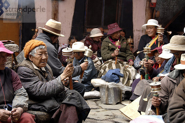 Viele tibetische Pilger sitzen im Hof mit Gebetsmühlen Lhasa Tibet China