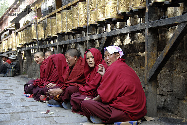 Buddhistische Nonnen sitzen unter Gebetsmühlen Potala Palast Kora Lhasa Tibet China