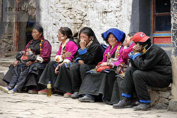 Tibetische Pilgerinnen in Tracht sitzen nebeneinander im Kloster Rongbuk Tibet China
