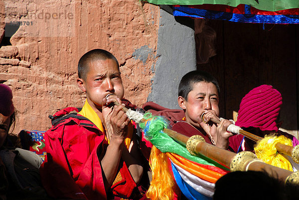Tibetischer Mönch und Nonne blasen in Trompeten mit dicken Backen Kloster Rongbuk Tibet China