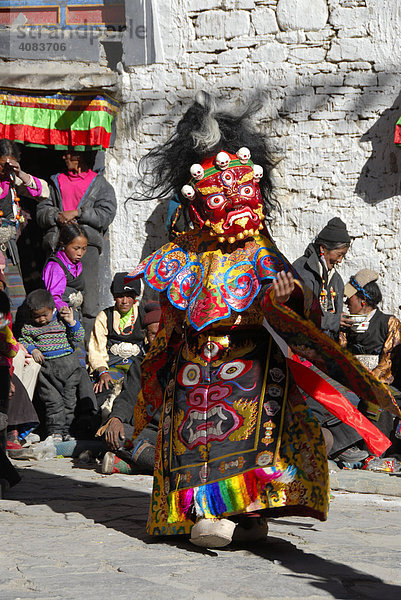 Mönch trägt schreckliche rote Maske und Gewand eines Dämon bei Festival in bunt geschmücktem Kloster Rongbuk Tibet China