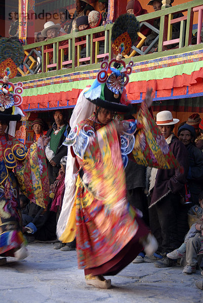 Bewegungsunschärfe Mönch tanzt mit schrecklicher Maske und Gewand eines Dämon inmitten vieler tibetischer Pilger bei Festival in bunt geschmücktem Kloster Rongbuk Tibet China