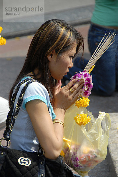 Junge Frau im Gebet mit Räucherstäbchen und Blüten Erawan Bangkok Thailand