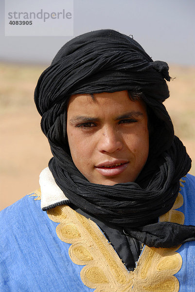 Portrait Tuareg Junge trägt blaues Gewand mit schwarzem Turban in Erg Chebbi Merzouga Marokko