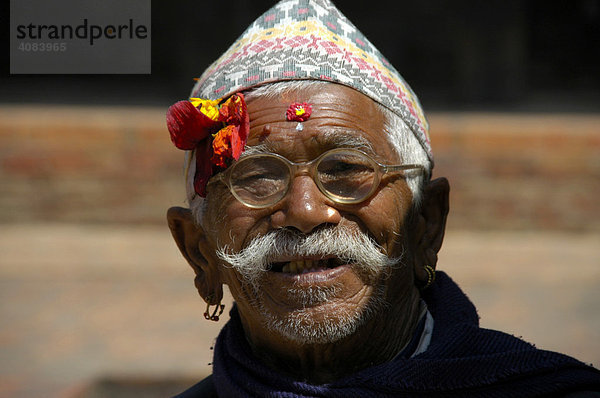 Portrait Newar Mann mit Brille und traditioneller Kopfbedeckung und Blume auf der Stirn Bhaktapur Nepal