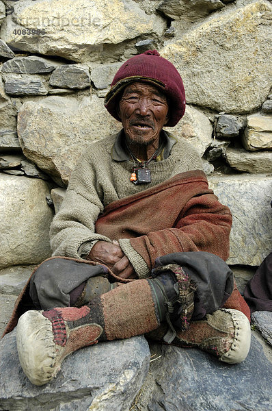Alter Mann mit Wollmütze und Stiefel aus vor einer Steinwand Phu Nar-Phu Annapurna Region Nepal