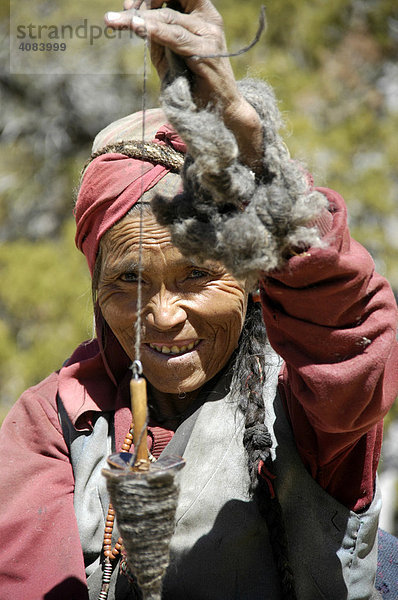 Portrait freundliche Tibeterin spinnt Wolle mit einer Spindel Nar-Phu Annapurna Region Nepal