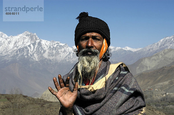 Portrait hinduistischer Pilger Sadhu mit Bart und Wollmütze vor schneebedeckten Bergen in Muktinath Mustang Annapurna Region Nepal