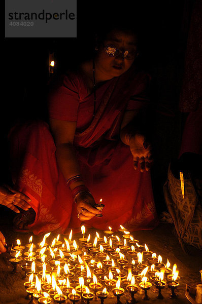 Frau wird erleuchtet von brennenden Butterlampen am Boden Kathmandu Nepal