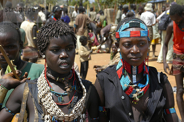 Zwei junge Frauen mit Muscheln und Ketten bunt geschmückt Markt in Keyafer Äthiopien
