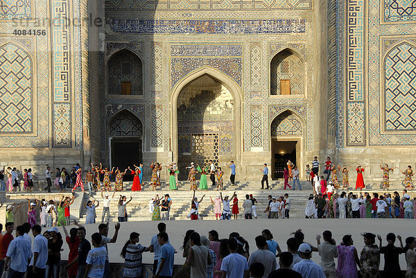 Junge Frauen tanzen vor der Medrese Sher-Dor Registan Samarkand Usbekistan