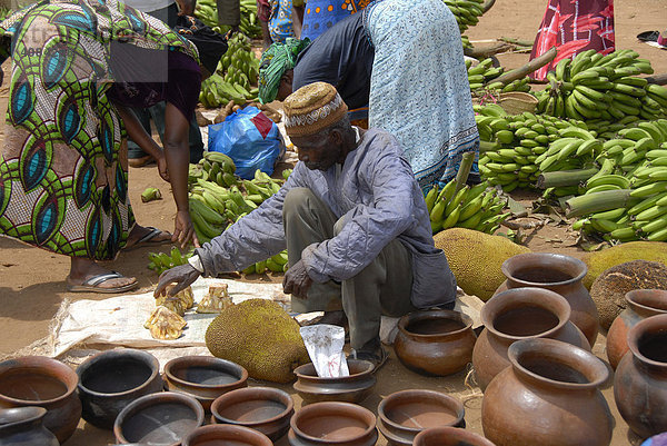 Einheimischer Mann verkauft Jackfruit Bananen und Töpfe auf dem Markt Tansania