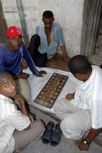 Einheimische junge Männer beim Brettspiel in einer Gasse in Stone Town Sansibar Tansania