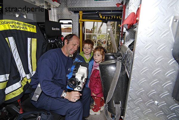 Kinder bekommen ein Wärmesuchgerät von einem Feuerwehrmann erklärt