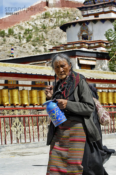 Pilgerin mit Teekanne vor Gebetsmühlen  Pälkhor Chöde Kloster in Gyantse  Tibet