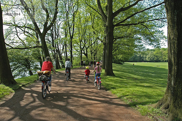 Familie faehrt Fahrrad auf einem Waldweg  Berger Anlagen  Gelsenkirchen  NRW  Nordrhein Westfalen  Ruhrgebiet  Deutschland