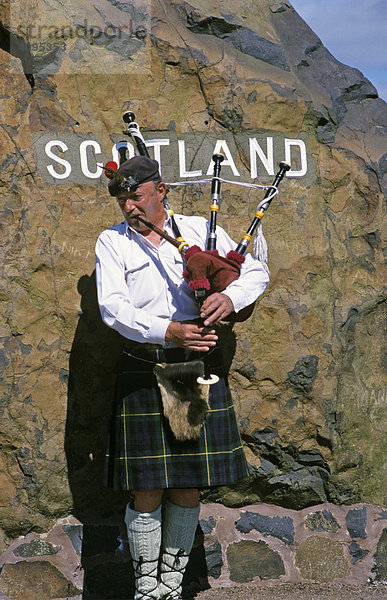 Dudelsackspieler vor Grenzstein an schottischer Grenze in Carter Bar Schottland Großbritannien