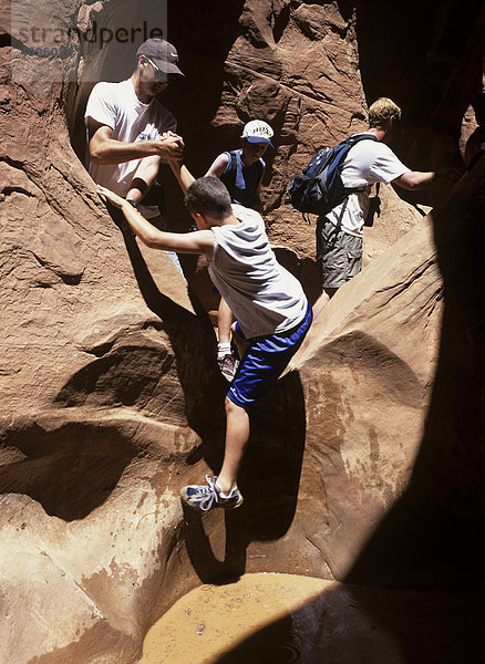Wanderer überwinden einen Wassertümpel im Peek a Boo Slot Canyon  Great Staircase-Escalante NP  Utah  Amerika