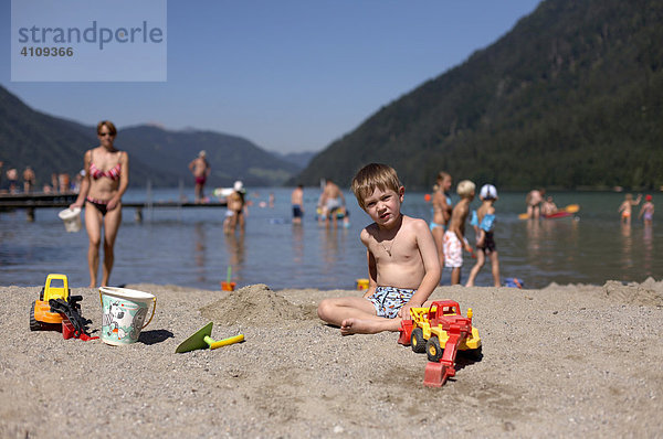 Kind (Bub) mit Spielzeugbagger am Weißensee in Kärnten  Österreich