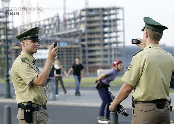 Polizist macht mit einem Fotohandy ein Erinnerungsfoto seines Kollegen
