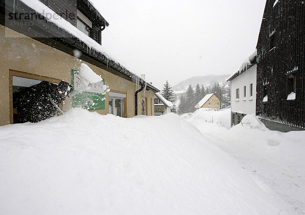Eingeschneite Pension Teuber in Oberwiesenthal - Frau enfernt Schnee am Fenster