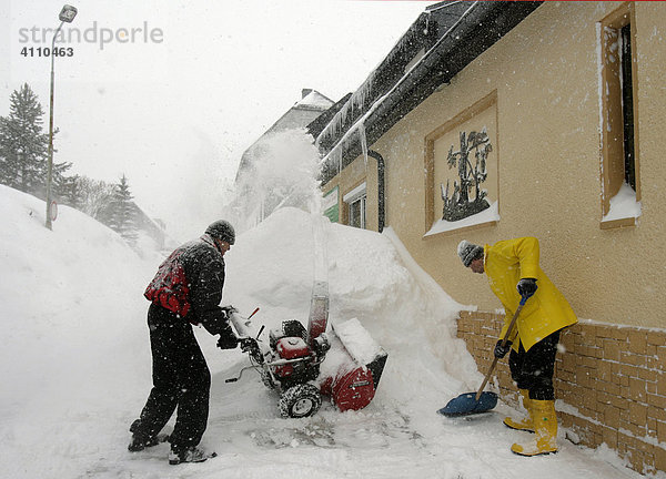 Männer räumen Schnee am Wohnhaus mit einer Schneefräsemaschine in Oberwiesenthal  Erzgebirge  Sachsen  Deutschland