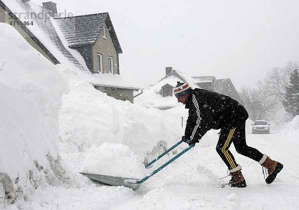 Mann räumt Schnee von der eingeschneiten Straße in Oberwiesenthal  Erzgebirge  Sachsen  Deutschland