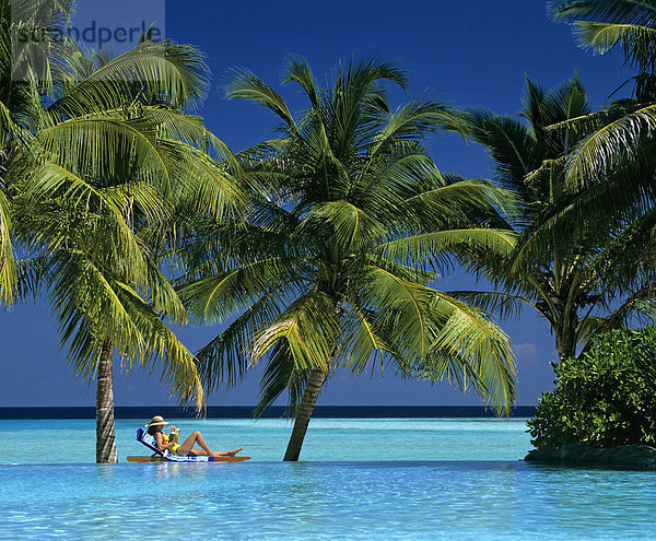 Junge Frau mit Drink im Liegestuhl  Schwimmingpool  Meer  Palmen  Sun-Island  Ari Atoll  Malediven