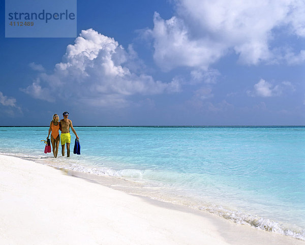Junges Paar mit Schnorchelausrüstung gehen im seichten Wasser  Sandstrand  Malediven