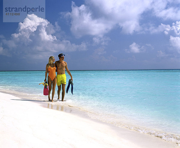 Junges Paar mit Schnorchelausrüstung gehen im seichten Wasser  Sandstrand  Malediven