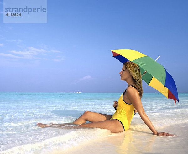 Junge Frau liegt im seichten Wasser  Strand  Sonnenschirm  Meer  Malediven