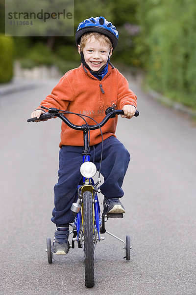 Eine Junge übt Radfahren mit Stützrädern